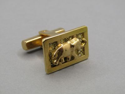 a picture of a gold cufflinke with an elephant on it