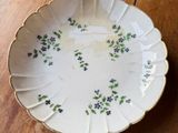 a white plate with purple flowers on it sitting on a wooden table