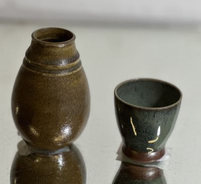 two small vases sitting on a table next to each other