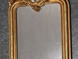 un miroir encadré d'or accroché au mur, sur lequel se reflète une image