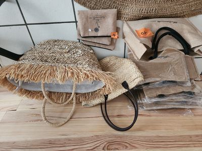 un sac en paille et un chapeau de paille posés sur un plancher en bois
