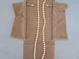 a long pearl necklace with a gold clasp on a brown bag