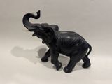 un petit éléphant noir debout sur une surface blanche