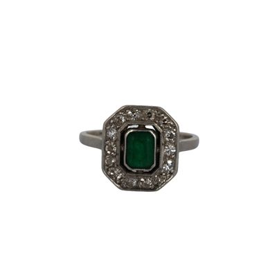 gros plan d'une bague avec une pierre verte entourée de diamants blancs
