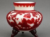 a red and white vase sitting on a wooden stand