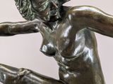 bronze statue of a woman holding a tennis racquet in one hand and a tennis ball in the other
