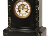 une horloge noire et dorée posée sur un socle en marbre