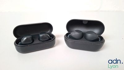 une photo montrant deux écouteurs noirs dans leur étui, posés sur une surface blanche