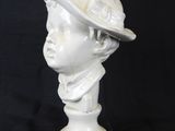 marble bust of a young boy wearing a hat on a black background