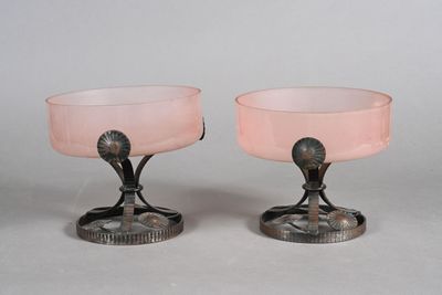 pair of pink glass goblets sitting on top of a metal stand