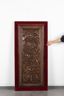 une femme debout près d'une grande porte en bois dans une pièce blanche