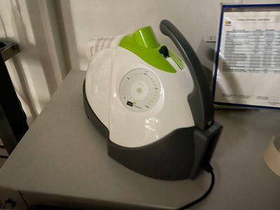 un fer à repasser à vapeur vert et blanc posé sur une table