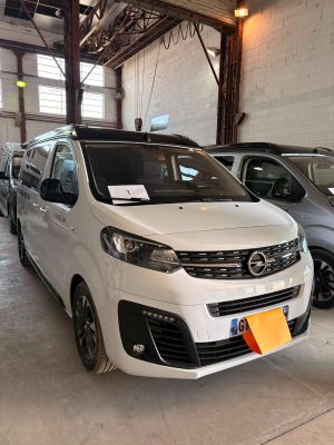 une camionnette blanche garée dans un garage à côté d'autres voitures