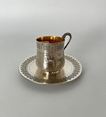 une tasse et une soucoupe en argent posées sur une assiette à soucoupe