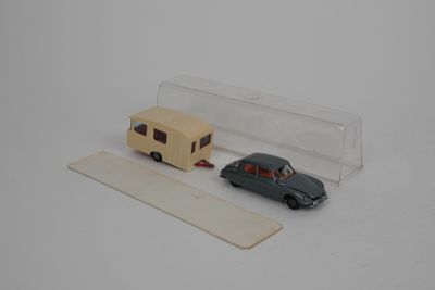 une petite voiture et une remorque miniatures posées sur une surface blanche