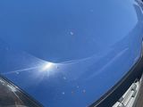 the front end of a blue car with a denting dent on it