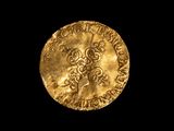 une pièce d'or sur laquelle est gravée une croix, sur fond noir