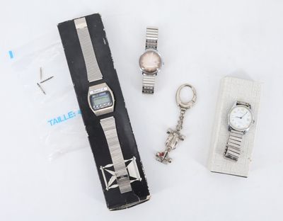 une montre, un porte-clés et un trousseau de clés posés sur une surface blanche