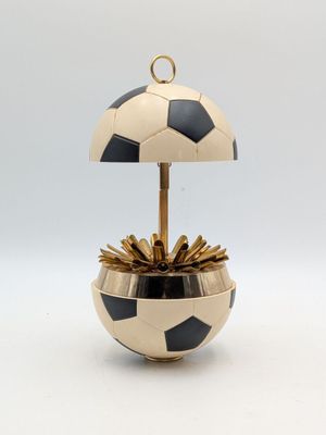 une image représentant un pot de fleurs en forme de ballon de football noir et doré sur fond blanc