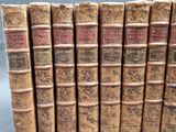 several old books are lined up in a row on a gray surface