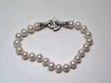 a close up of a white pearl bracelet with a silver clasp
