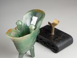 a green vase sitting next to a small black object