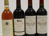 four bottles of wine are lined up in a row on a white surface