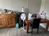une petite table avec un ventilateur dans un coin de la pièce