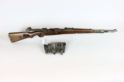 un fusil avec un canon en bois et un chargeur, posé sur une surface blanche