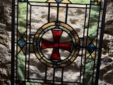 stained glass window in a stone wall with a cross in the center