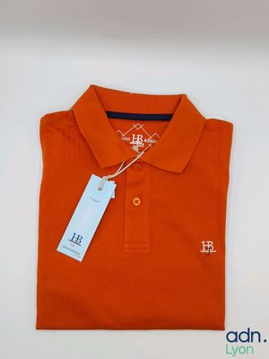 un gros plan sur un polo orange muni d'une étiquette