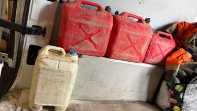 a pile of gas cans sitting on the side of a wall