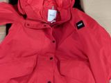 La veste est rouge et comporte une capuche qui en fait partie intégrante.