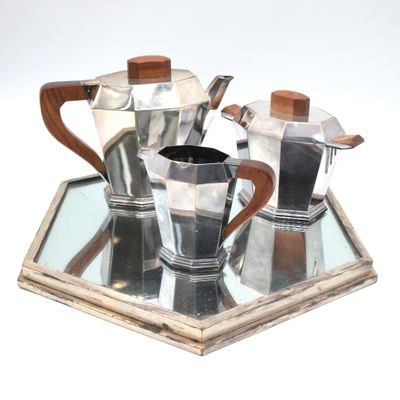 a silver tea set on a mirrored tray with a wooden handle