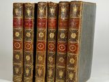 three old books sitting on top of each other on a white surface