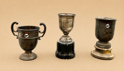 trois tasses en argent posées l'une à côté de l'autre sur une table