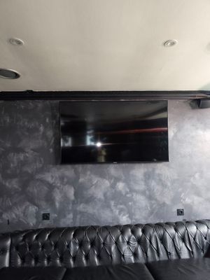 a black leather couch sitting in front of a flat screen tv
