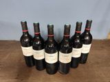 six bottles of wine are lined up on a wooden table