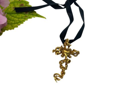 une croix en or sur un ruban noir, avec une fleur en arrière-plan
