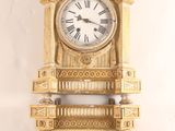une horloge dorée accrochée au mur, avec des chiffres romains