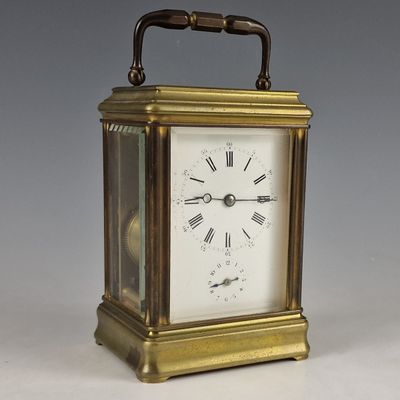 une petite horloge en laiton avec des chiffres romains sur le cadran