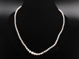 a white pearl necklace on a black mannequin