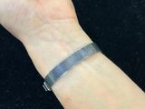 a woman ' s arm with a silver bracelet on it