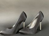 pair of women ' s grey high heeled shoes on a gray background