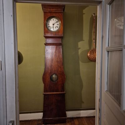 une horloge de parquet posée dans l'embrasure de la porte d'une maison