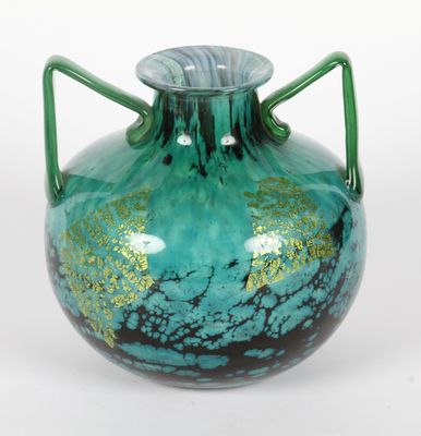 un vase vert muni d'une anse sur fond blanc