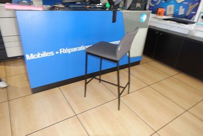 une photo du comptoir d'un atelier de réparation de téléphones portables, avec une chaise placée devant