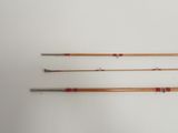 three old fishing rods are lined up on a white surface