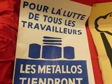 two signs on a red chair that read pour la lutte de tous les travailleurs