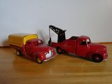 deux camions miniatures posés l'un à côté de l'autre sur un plancher en bois